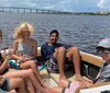 Two people are smiling for a selfie on a boat with waterfront properties in the background