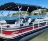 A pontoon boat with a canopy is docked in calm blue waters on a sunny day