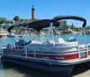 A pontoon boat with a canopy is docked in calm blue waters on a sunny day