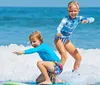 Two children are happily surfing together on a bright sunny day at the beach