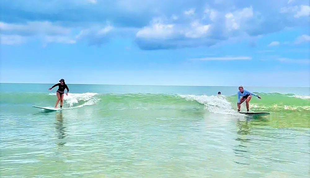 Two people are surfing gentle waves on a sunny day with clear skies at a beach