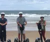 Two people are riding Segways on a wet beach with a large pier structure in the background