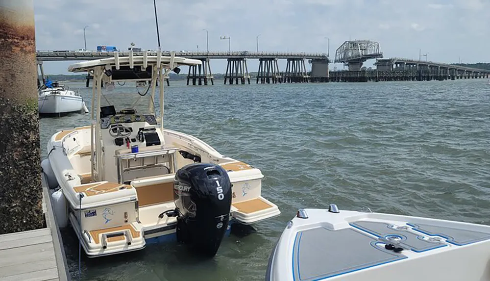 A boat is moored near a dock with a bridge in the background over a body of water