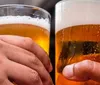 Two hands holding pints of beer in a social toast or cheers gesture