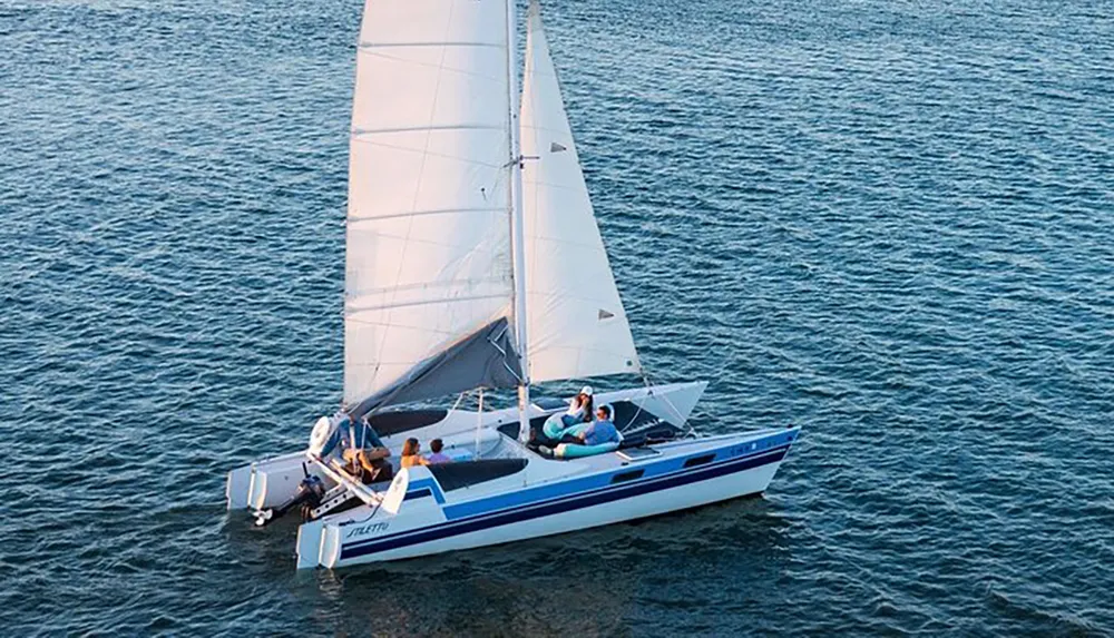 A sailboat with several individuals on board is gliding over a calm body of water