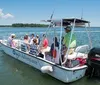 A group of people are enjoying a boat ride on a clear day in a vessel named Osprey Adventurer powered by a Suzuki outboard motor