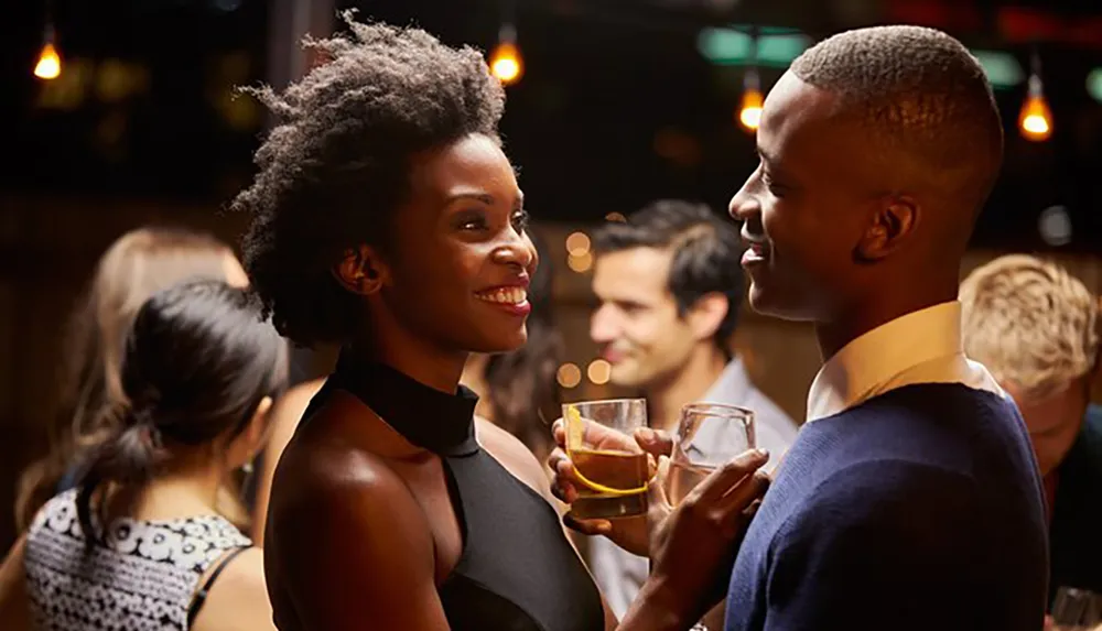 Two people are enjoying a conversation while holding drinks at a social event