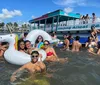 A group of people are enjoying a sunny day in the water with inflatable rafts near a Staying Afloat Party Boat