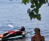 A group of people is enjoying stand-up paddleboarding in a sunny calm waterway with a luxurious mansion and a yacht in the background