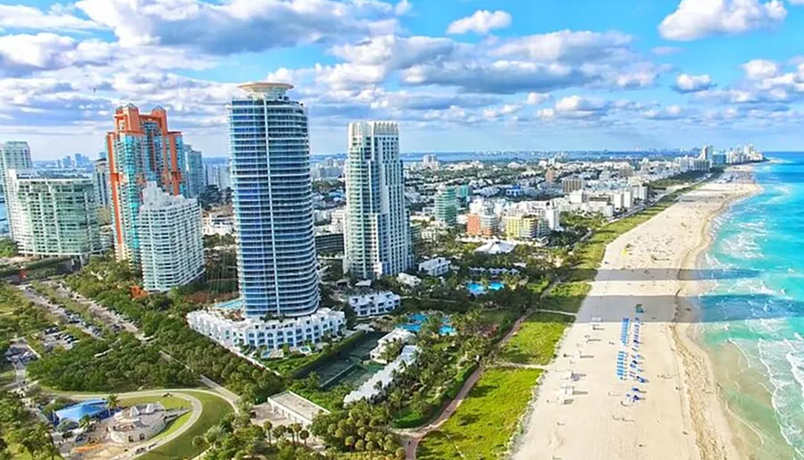 The image shows a scenic aerial view of a coastal city with modern high-rise buildings alongside a long sandy beach and clear blue waters.