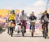 A group of smiling people with one child are enjoying a sunny bike ride together wearing helmets for safety