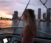A woman is admiring a sunset from a boat with a city skyline in the background