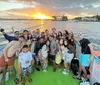 A joyful group of people are taking a selfie on a boat during a sunset