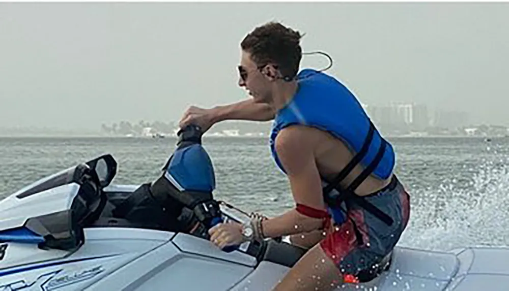 A person is riding a jet ski on the water creating a spray as they speed along