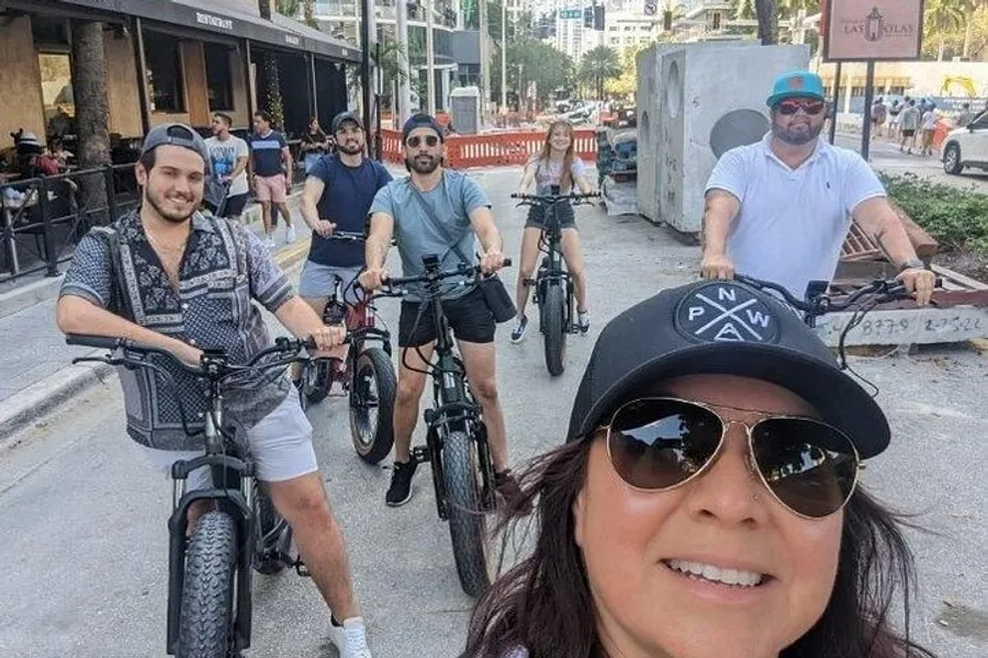 A group of people are happily posing for a selfie while on a bike ride in an urban setting.