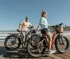 A group of people wearing helmets stands with their fat-tire bicycles on a coastal trail posing for a photo with a bridge and the ocean in the background