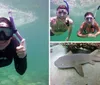 A person in a wetsuit is giving two thumbs-up while snorkeling underwater