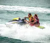 Two people are riding a jet ski across choppy water creating a spray behind them