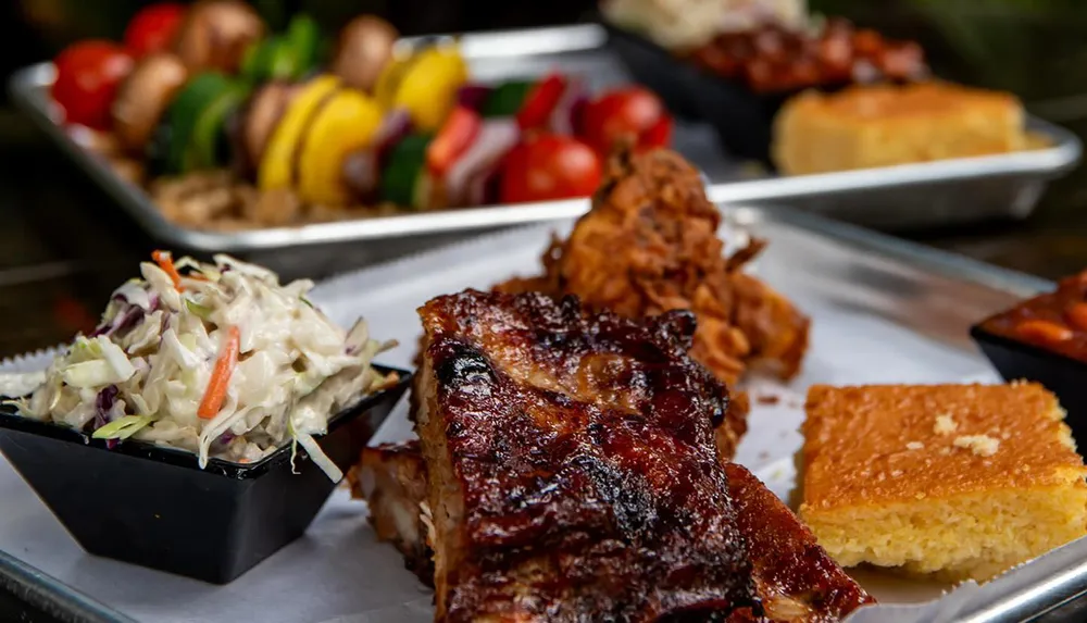 A tray with barbecued ribs coleslaw cornbread and a skewer of grilled vegetables suggests a delicious BBQ meal