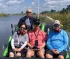 A group of people in matching blue shirts are joyfully raising their hands while on a boat ride under a clear blue sky