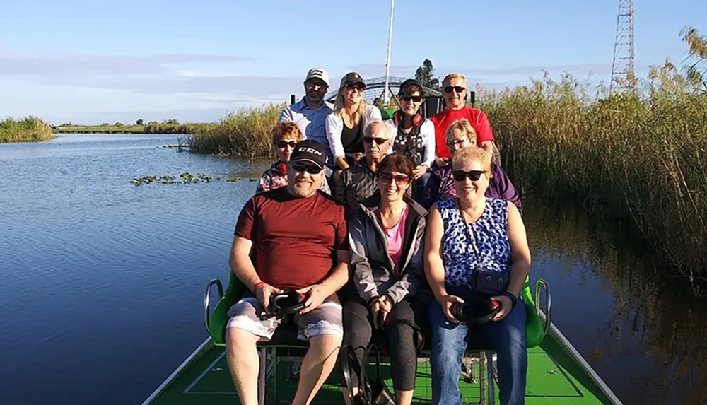 A group of people are smiling for a photo while on a boat tour surrounded by calm waters and lush vegetation