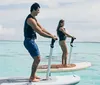 A man and a woman paddleboarding on a calm clear ocean