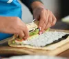 A person is preparing sushi by rolling ingredients in seaweed on a bamboo mat