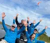 A group of happy people wearing blue shirts are raising their hands in the air while seated on a boat