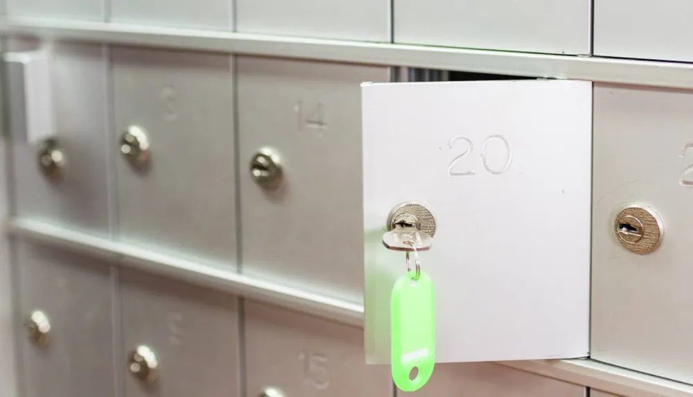 A locker number 20 is open with a key inserted into the lock and a green tag attached to it amongst a series of closed lockers