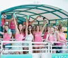 A group of people wearing matching pink tank tops that say bride and bride tribe are enjoying a celebration on a boat