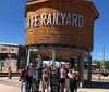 A group of people is posing for a photo in front of a rustic-looking entrance with the words THE RAILYARD in Santa Fe New Mexico