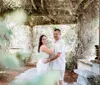 A couple is posing affectionately under a vine-covered pergola in a lush garden setting