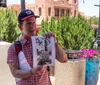 A person is showing a framed photograph to a couple in an outdoor park-like setting possibly during a tour or presentation