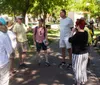 A person is showing a framed photograph to a couple in an outdoor park-like setting possibly during a tour or presentation