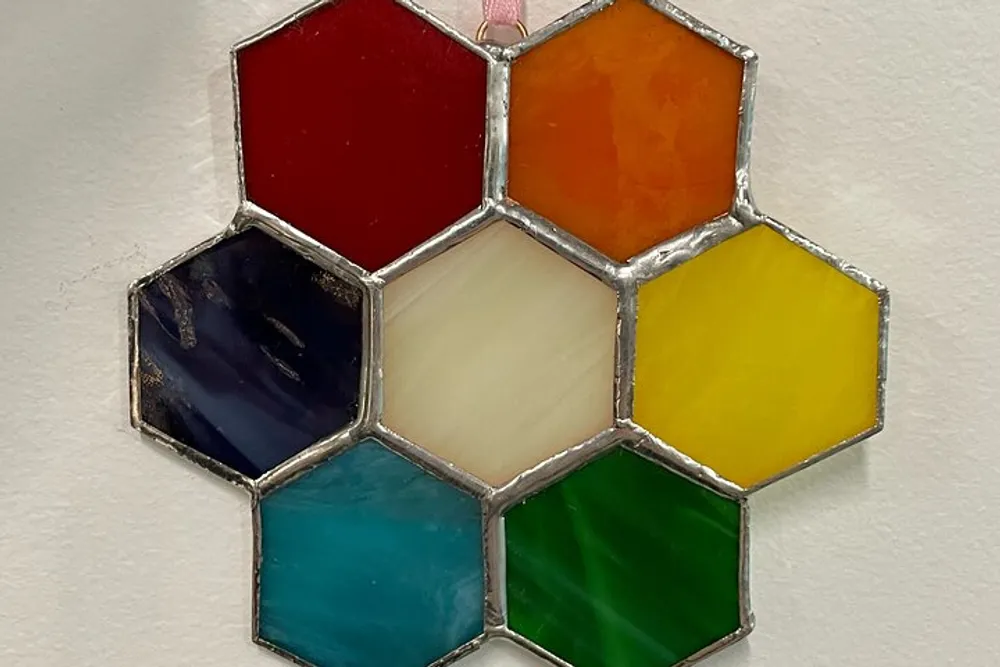 The image shows a collection of hexagonal stained glass panels in various colors assembled together to form a honeycomb-like pattern