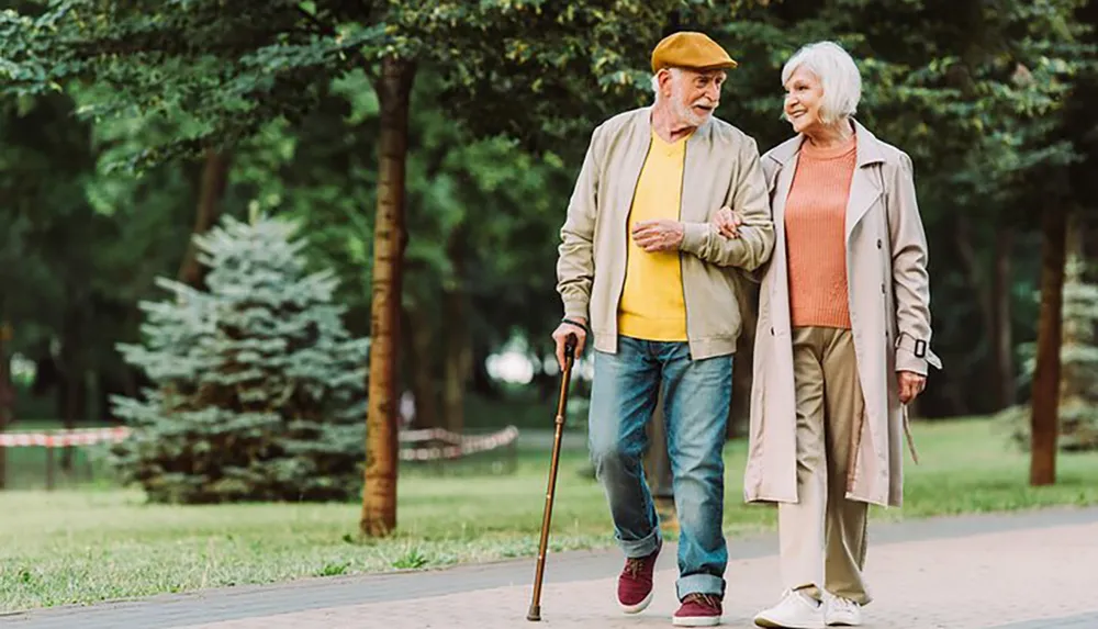 An elderly couple is enjoying a leisurely walk together in a lush green park