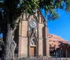 A pair of smartphones displaying a tour guide application are superimposed in the foreground of an image featuring a historic church with twin bell towers