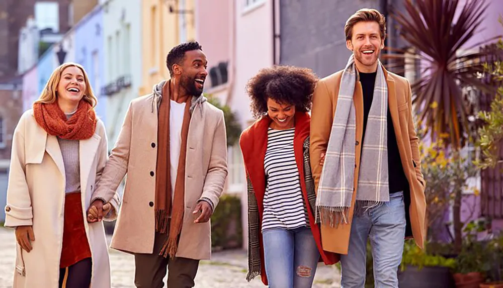 Four friends are walking down a colorful urban street joyfully engaging with each other in a casual autumnal setting