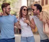 Four friends are laughing and enjoying a lively conversation on a sunny urban street