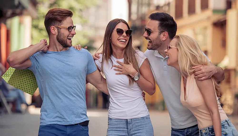 Four friends are laughing and enjoying a lively conversation on a sunny urban street