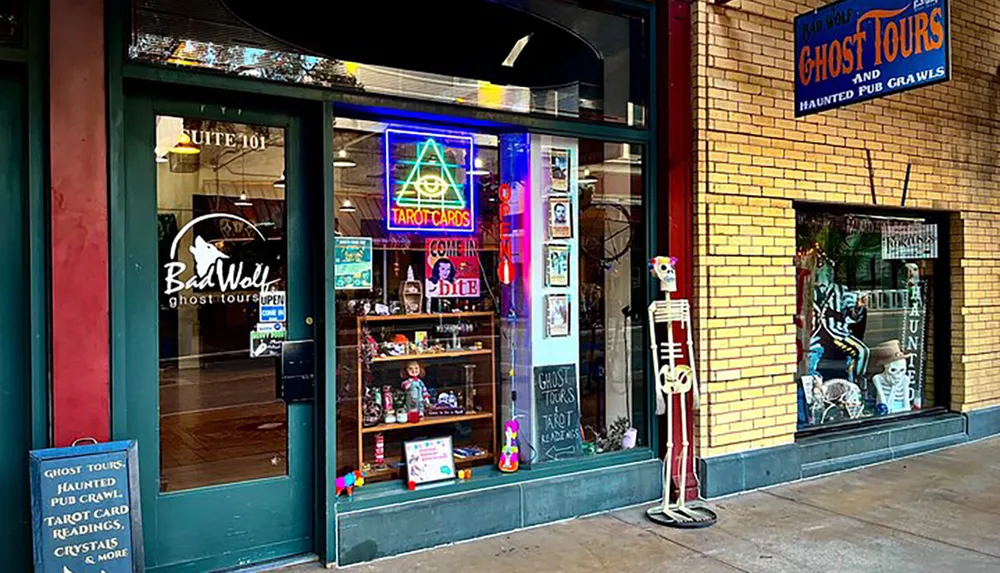 A quirky storefront offers ghost tours and has a skeleton decoration out front alongside neon signs for tarot card readings