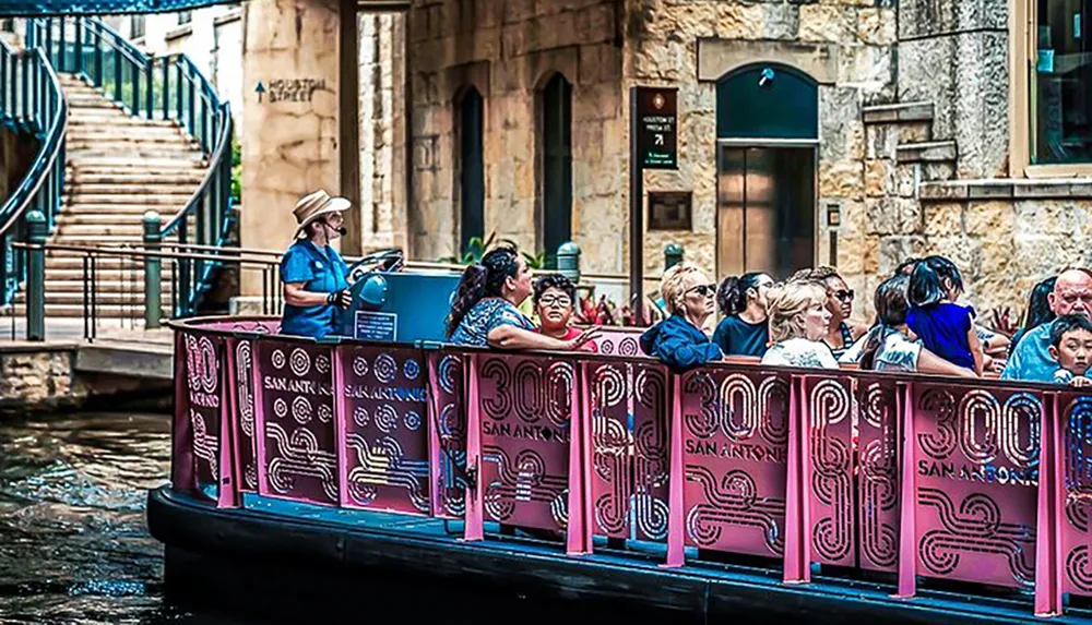 A tour guide is leading a group of passengers on a San Antonio river cruise with guests listening and observing their surroundings