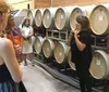 A group of people is attending a wine barrel tasting or winery tour guided by an expert