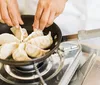 A person is pan-frying dumplings on a stovetop