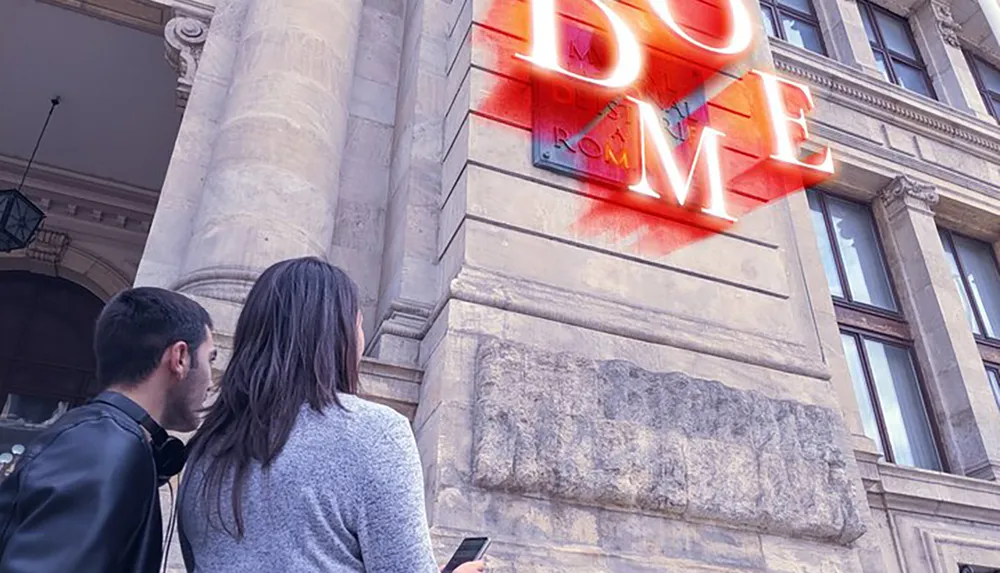 Two people are looking at a neon sign that spells LOVE on the side of a building