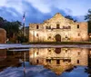 The Alamo Mission in San Antonio Texas is illuminated in the early evening and reflected in a smooth water surface in front of it