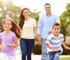 A happy family with two adults and two children are enjoying their time outdoors with the children sitting on the adults shoulders