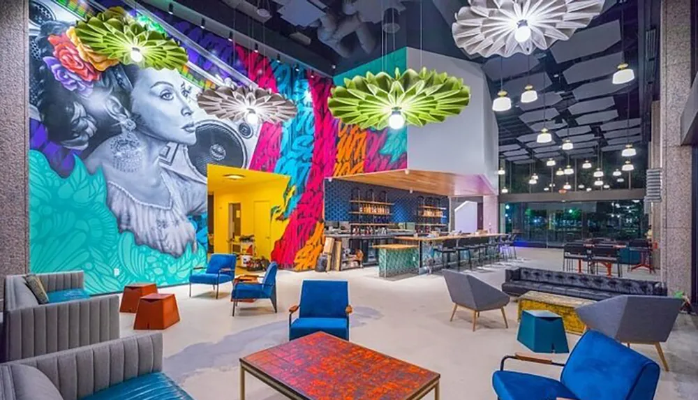 A vibrant and modern interior space featuring colorful furniture an elaborate wall mural of a woman with flowers artistic lighting fixtures and an inviting bar area