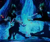 Two dancers are captured in mid-air against a vibrant blue and pink neon-lit background creating a dynamic sense of movement and energy