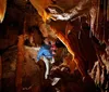 A family is admiring an underground pool in a beautifully lit cave with intricate rock formations surrounding them